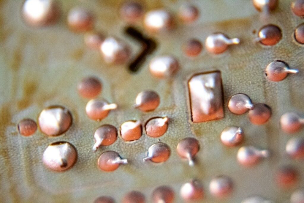 Close-up of copper-colored droplets and rectangular pieces on a textured surface