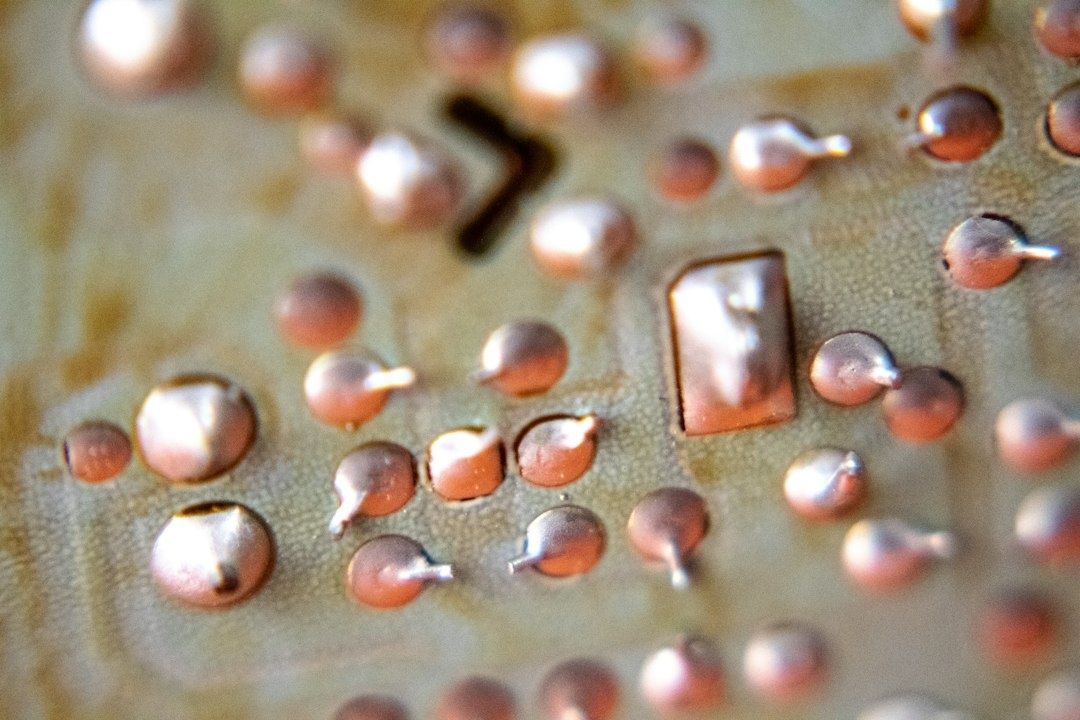 Close-up of copper-colored droplets and rectangular pieces on a textured surface